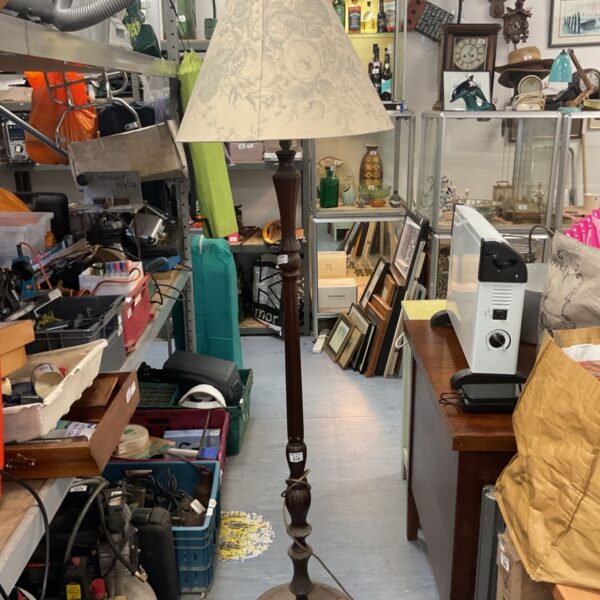 Vintage wooden standard lamp with cream lampshade in a room setting.