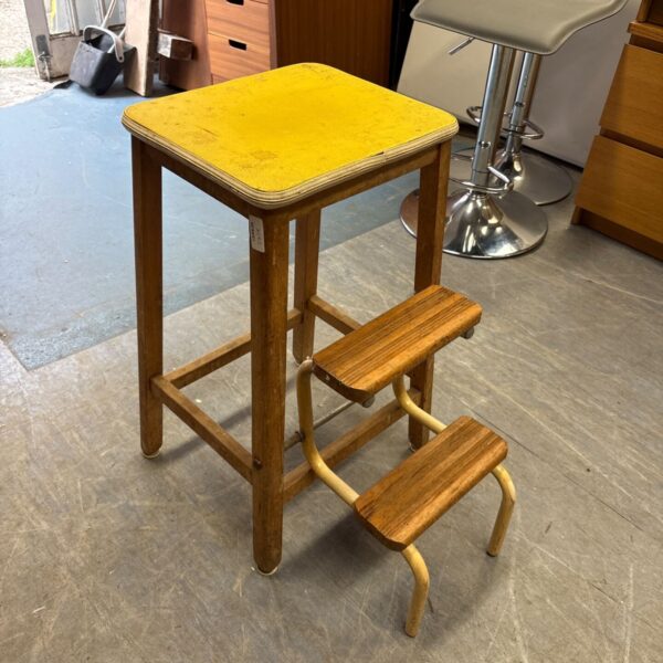 Vintage wooden step stool with yellow top and metal legs.