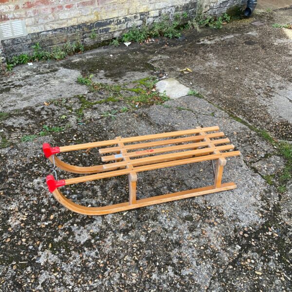 Vintage wooden toboggan with red accents, a classic snow sled.