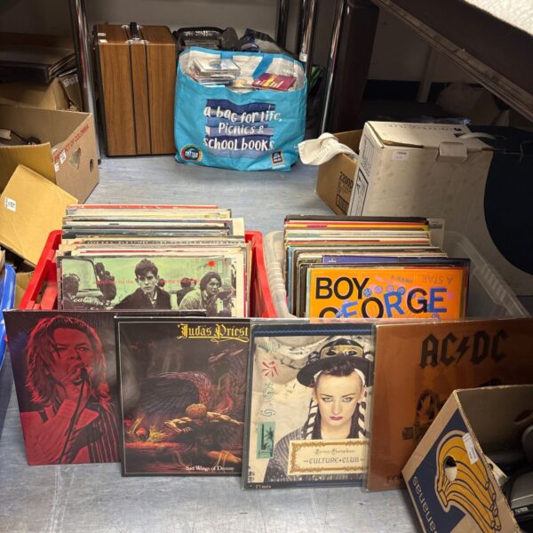 Vinyl record collection featuring AC/DC, David Bowie, and Judas Priest LPs.