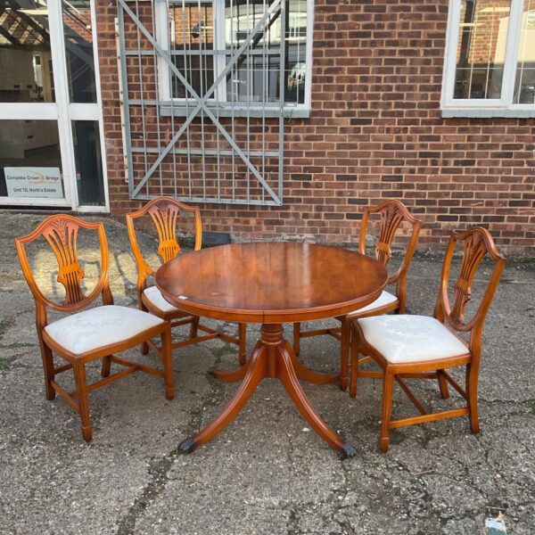 Vintage walnut extending dining table with four shield back chairs.