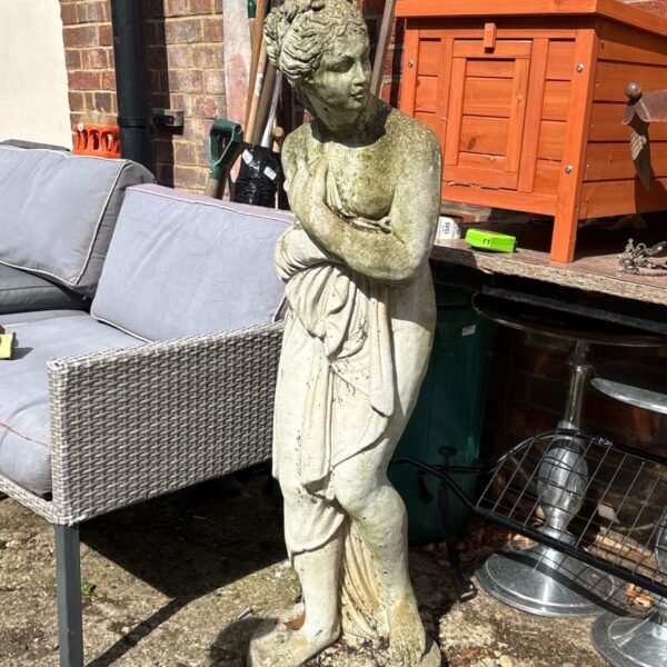 Weathered cast stone garden statue of a draped female figure.