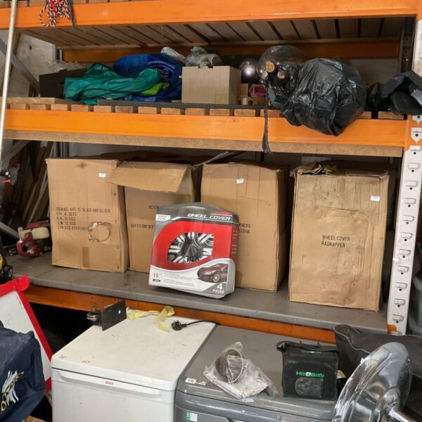 Stack of four boxes containing silver 15 inch wheel covers.