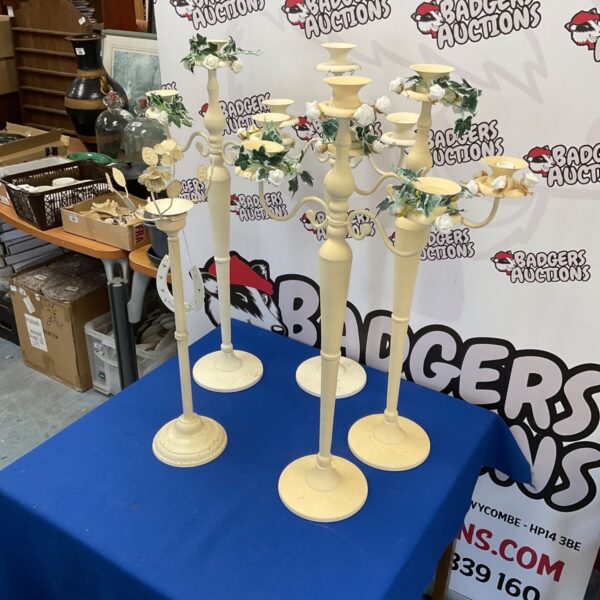 Five white wedding candle sticks displayed on a patterned surface.