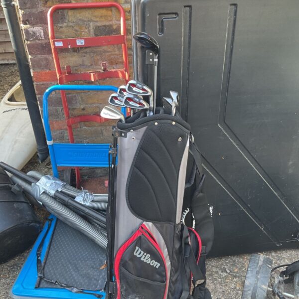 Black and red Wilson golf bag with drivers visible nearby.
