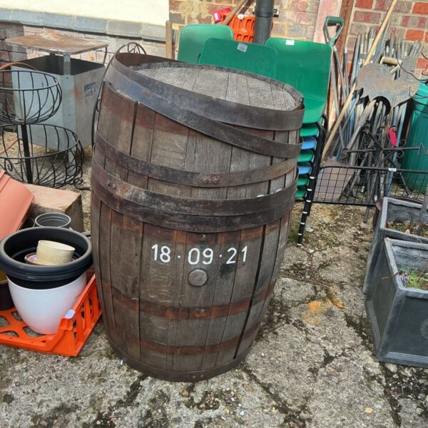 Vintage wooden barrel in a garden setting, awaiting restoration.