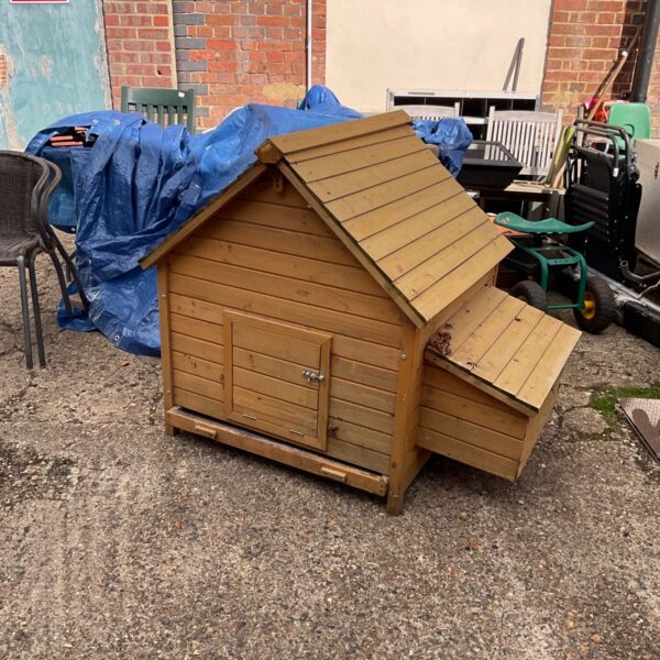 Rustic wooden chicken coop in a garden setting.