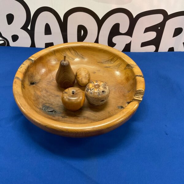 Rustic wooden fruit bowl filled with wooden apples and pears.