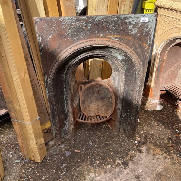 Antique wrought iron fireplace insert with ornate detailing.