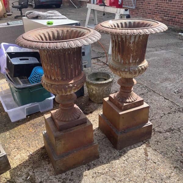 Vintage wrought iron garden urns displayed outdoors.