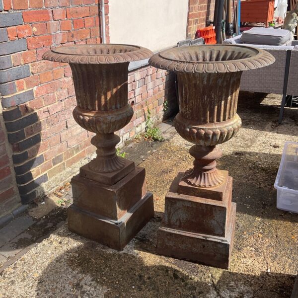Antique wrought iron garden urns displayed outdoors.