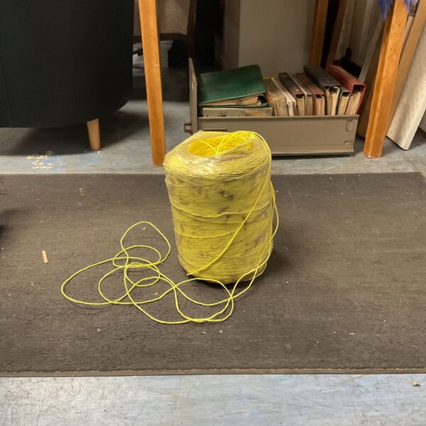 Large coil of yellow polypropylene baler twine for farm use.