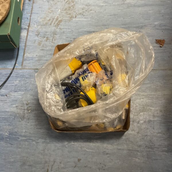 Box of 110V industrial electrical plugs, connectors and black cable in plastic bag