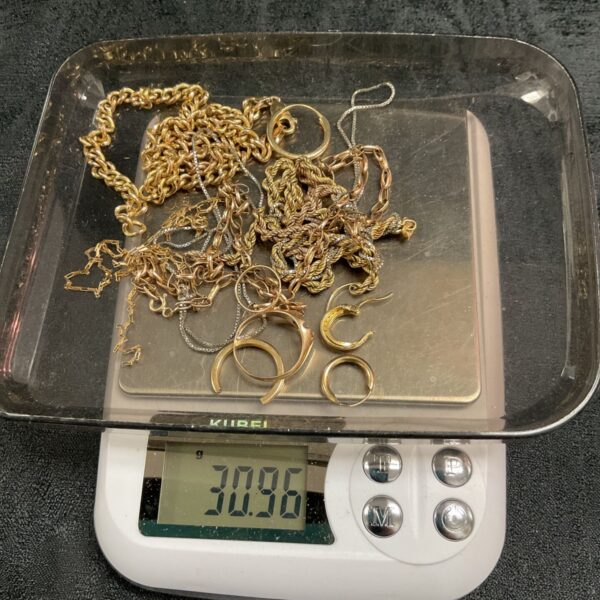 Tangled 9ct gold scrap chains, rings and earrings on digital scale