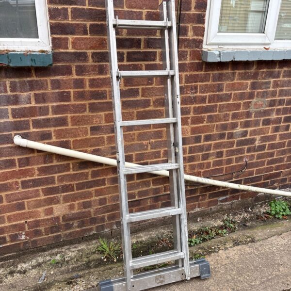 Aluminium extending ladder leaning against a brick wall.