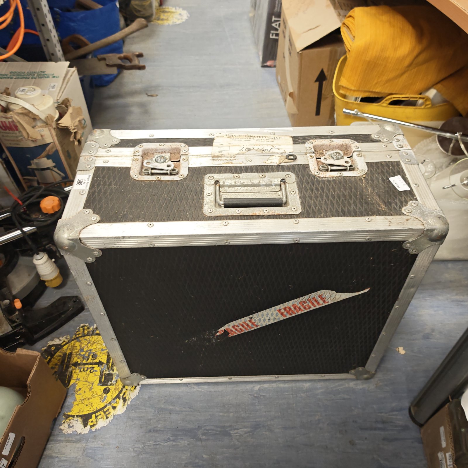 Squared aluminium flight case with handle and clasps, showing signs of wear.