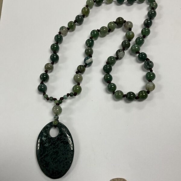 Antique green hand knotted bead necklace with large oval green pendant on dark cord
