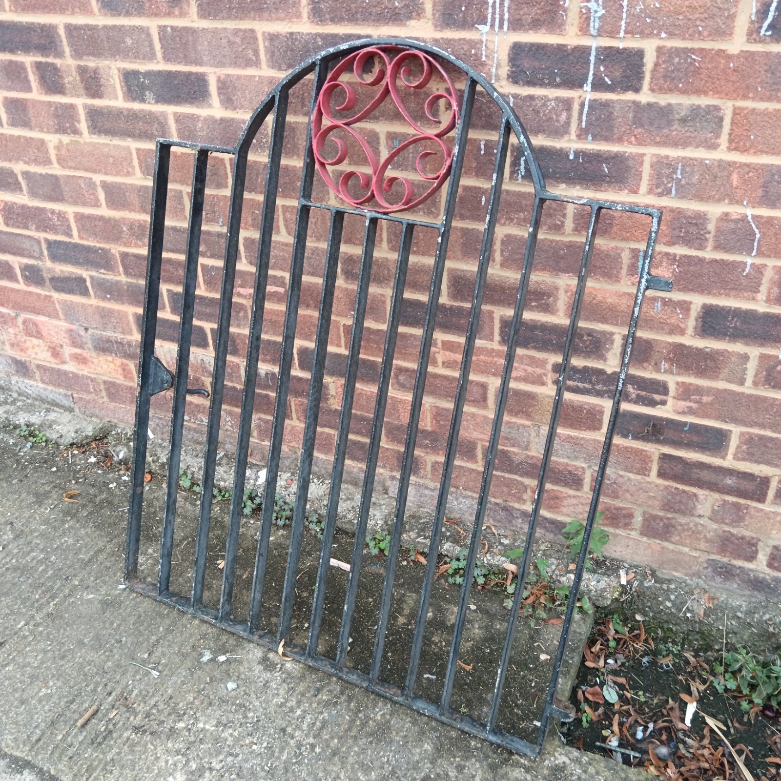 Antique iron garden gate with decorative arched design and floral detail.