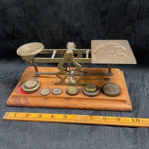 Antique brass letter post scales with weights on wooden base.