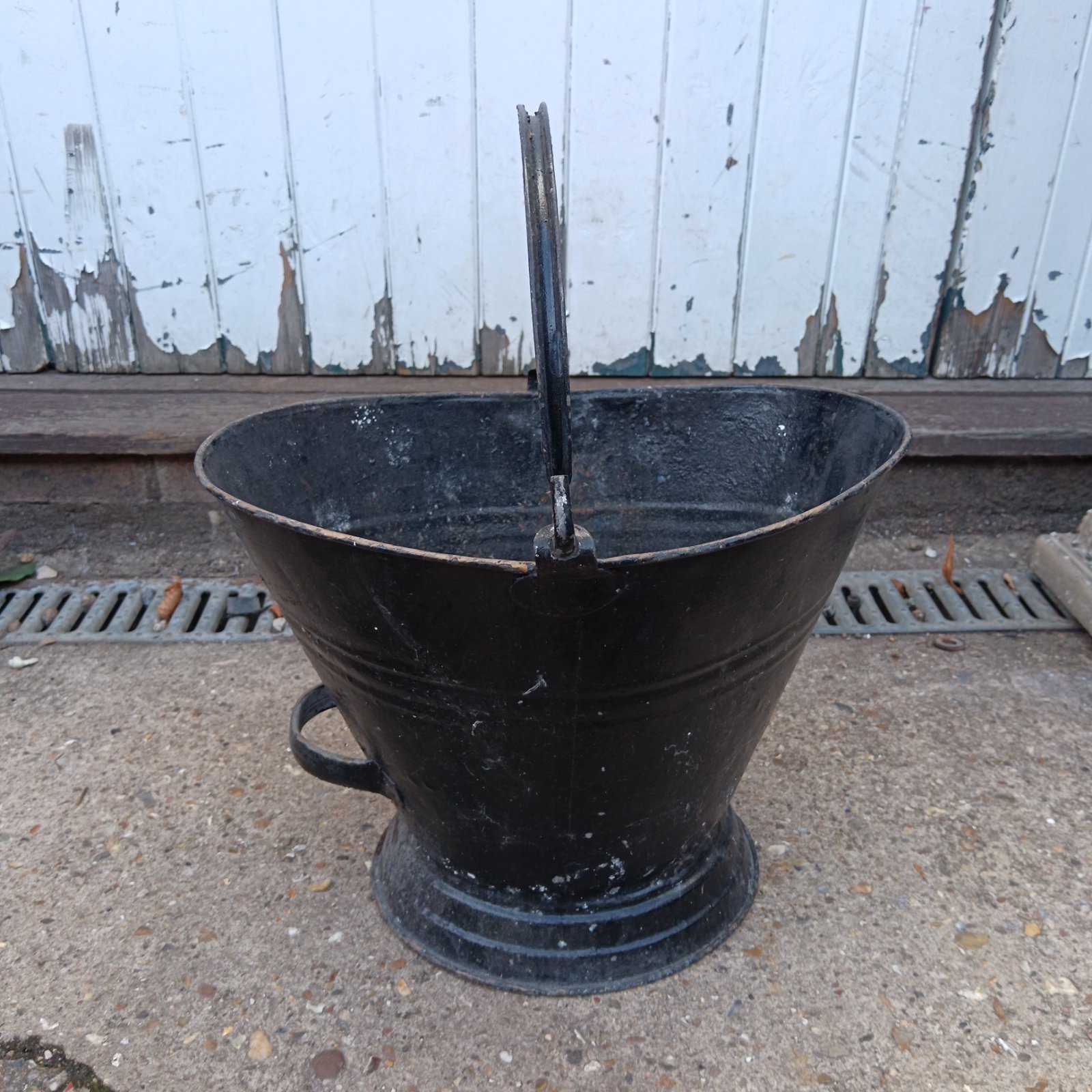Antique metal coal bucket with handle for fireplace use.