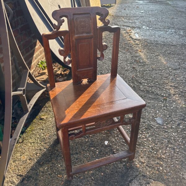 Antique oriental carved wood chair with detailed floral carvings.