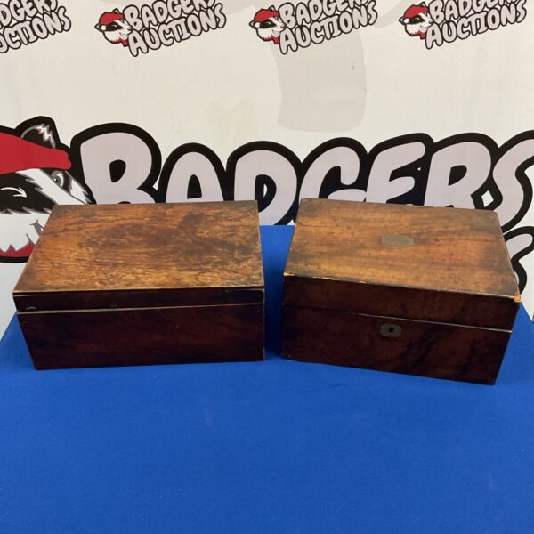 Two closed antique wooden boxes with brass detailing on blue surface