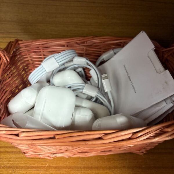 Reproduction Apple headphones and charging cables in a basket.