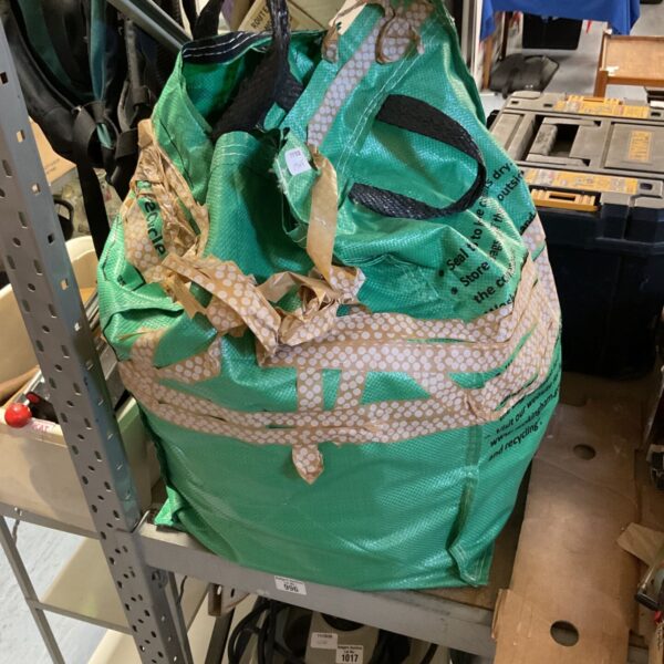 Green bag filled with assorted items, a mixed lot for sale.