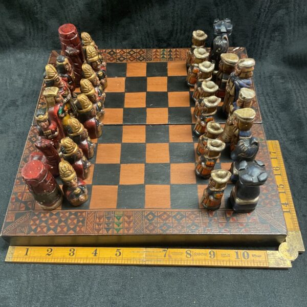 Vintage Aztec chess set with colourful ceramic pieces on a wooden board.