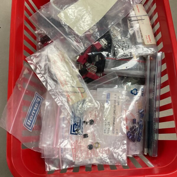 Red basket of assorted electronic components in clear bags, including capacitors and switches