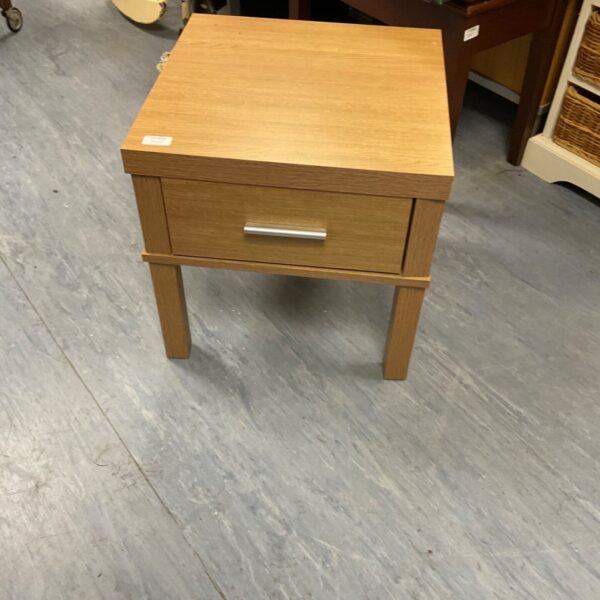 Small wood effect bedside cabinet with a single drawer.