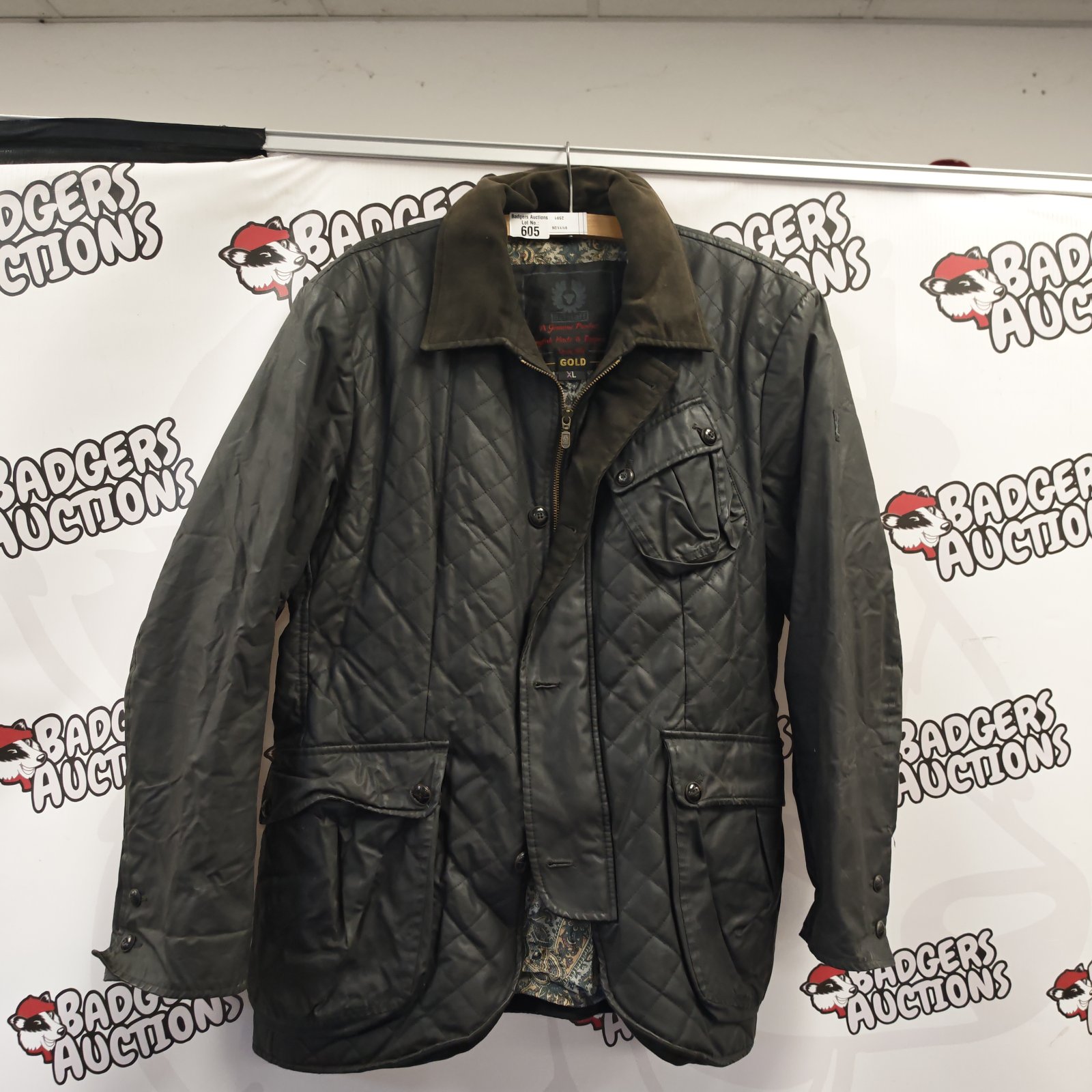 Dark green Belstaff gold quilted wax jacket size XL hanging on display