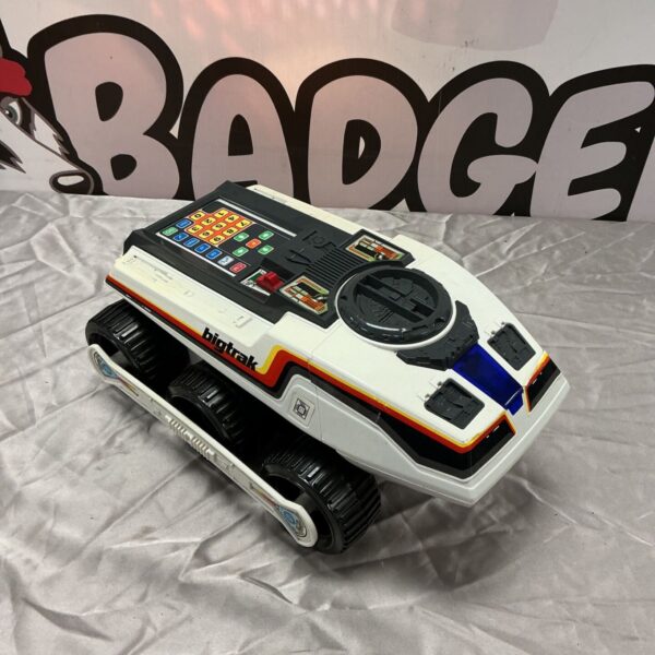 White Bigtrak programmable vehicle with black tracks and keypad on a grey fabric surface
