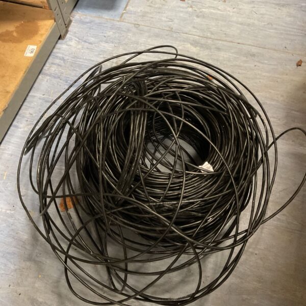 Loose coil of black flexible electrical wire on a workshop floor