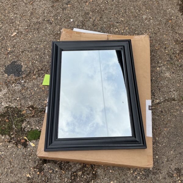 Black framed wall mirror reflecting the sky.