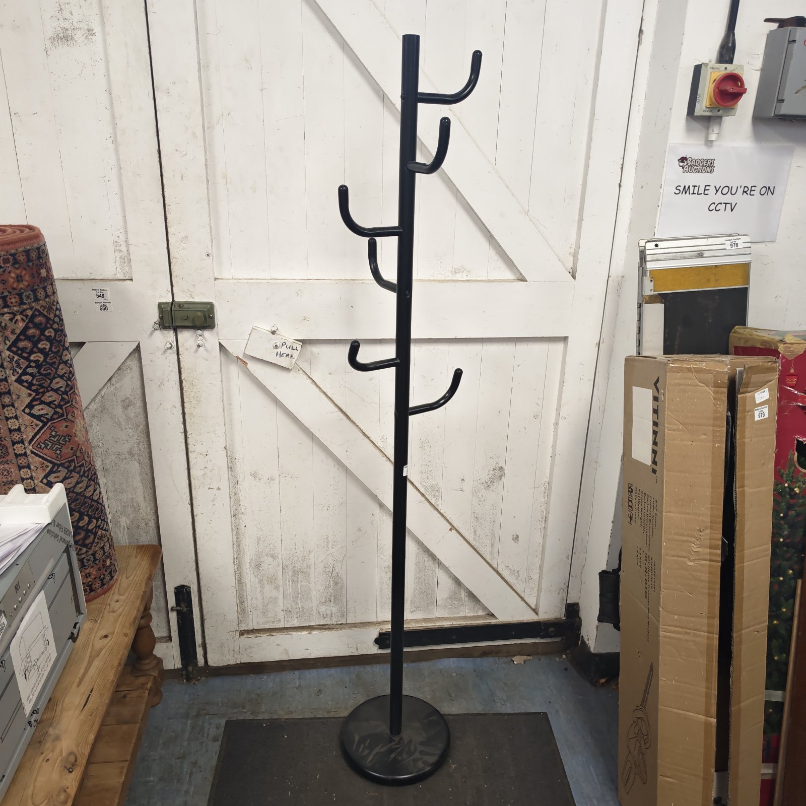 Black metal coat stand with multiple hooks for coats and hats.