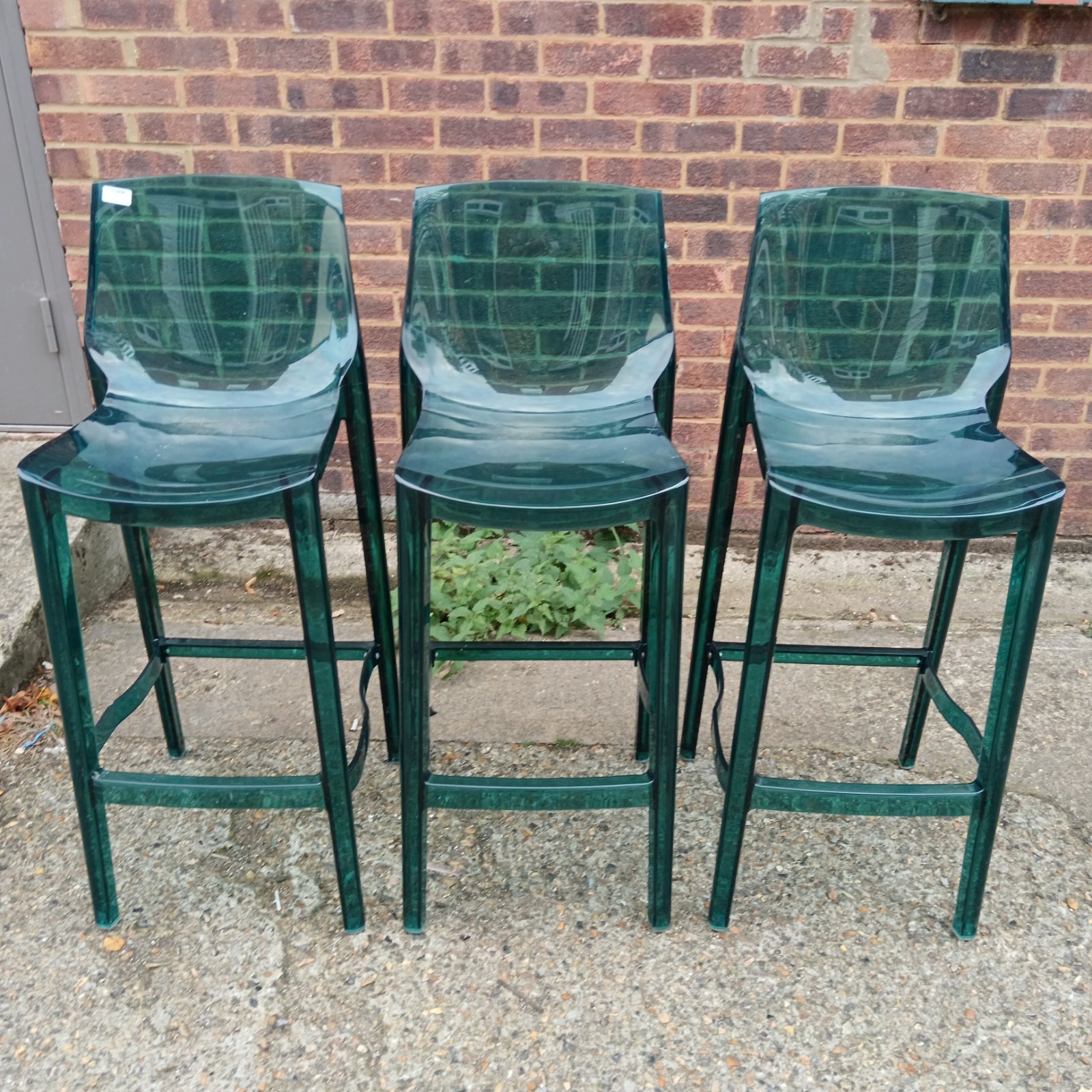Three blue perspex bar stools in a modern setting.
