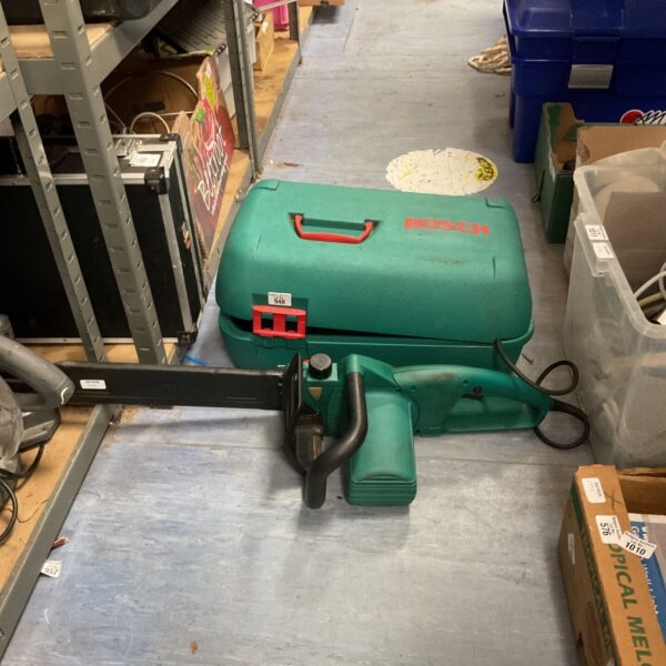 Green Bosch 060 electric chainsaw, corded power tool for garden use.