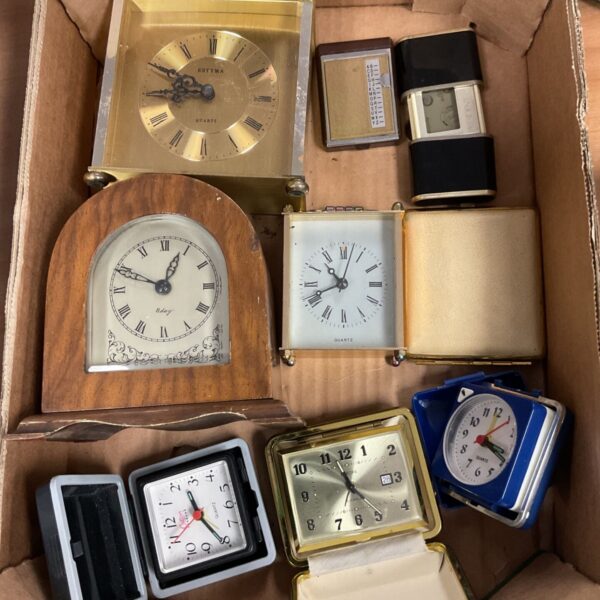 Box of assorted clocks including brass carriage clock and wooden mantel clock