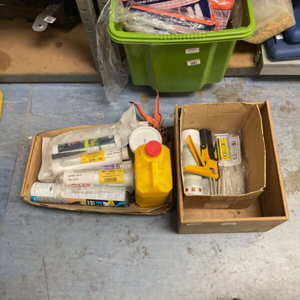 Box of assorted construction and automotive adhesives and sealant tubes with caulking gun