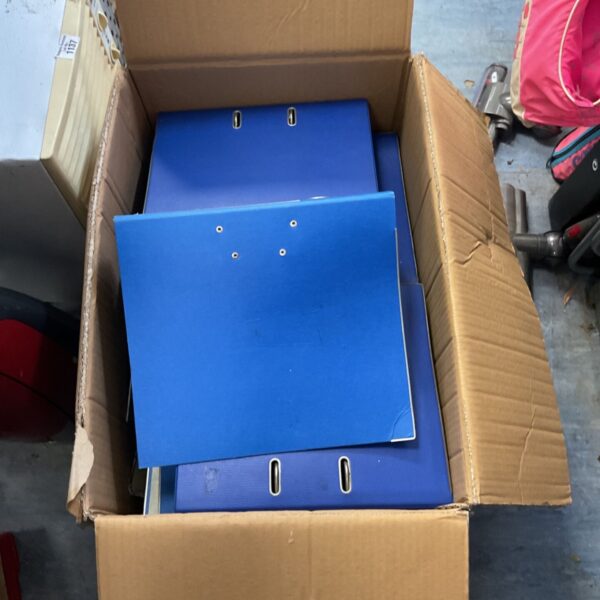 Open cardboard box containing a quantity of blue folders with metal fittings