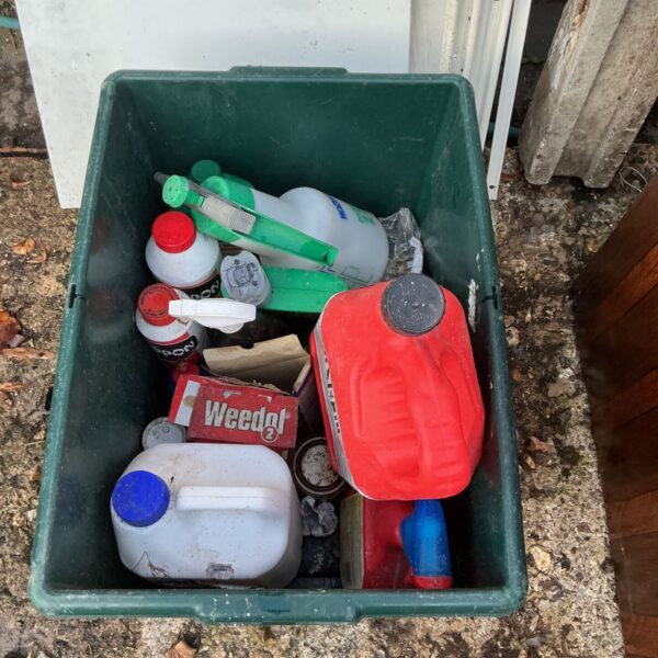 Green tub holding box of garden chemicals including Weedol 2 carton and plastic bottles