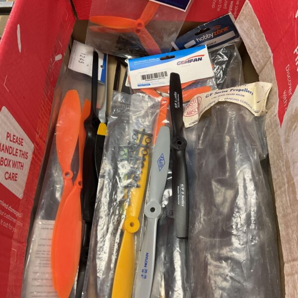 Cardboard box containing mixed propellers and drone rotors, including orange and black pieces