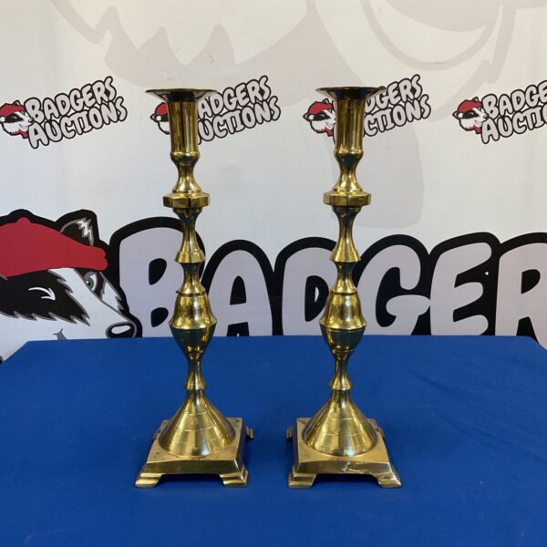 Pair of vintage brass candlesticks on a dark surface.