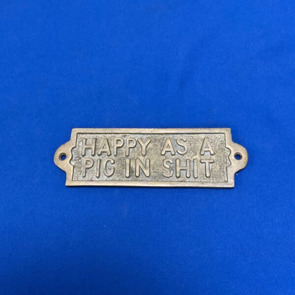 Vintage brass plaque reading "Happy as A pig" for wall decor.
