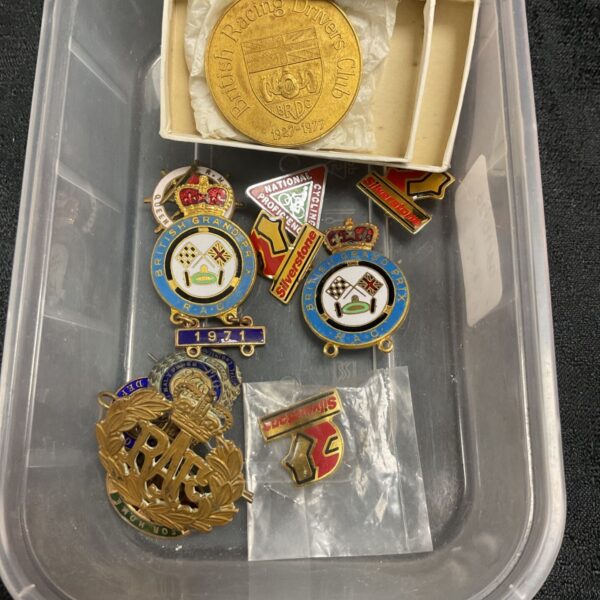Vintage British Grand Prix pin badge collection with military themes.