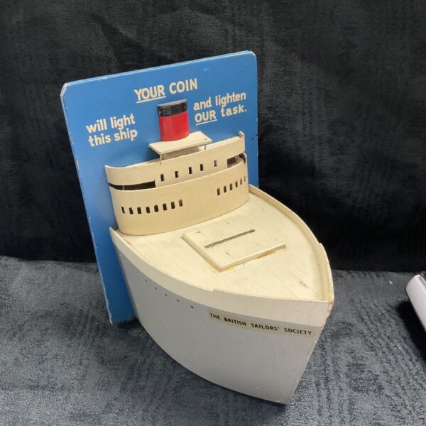 British Sailors' Society donation money box shaped as a ship on blue backing board