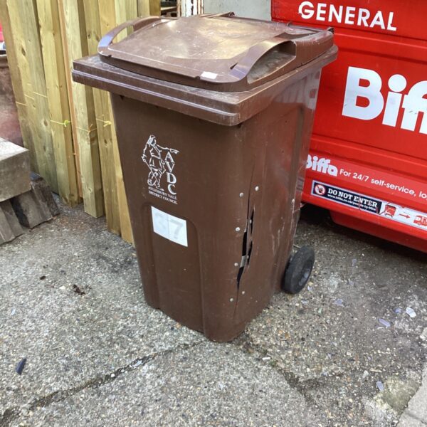 Brown wheelie bin outdoors, showing signs of use.