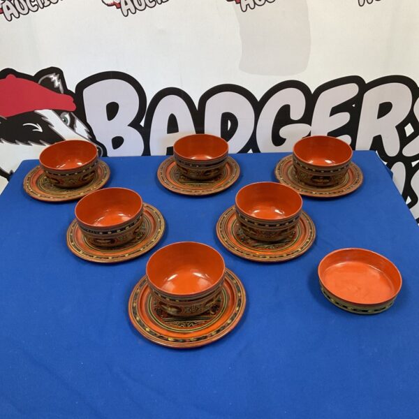 Vintage Burmese lacquerware set with red plates and bowls.