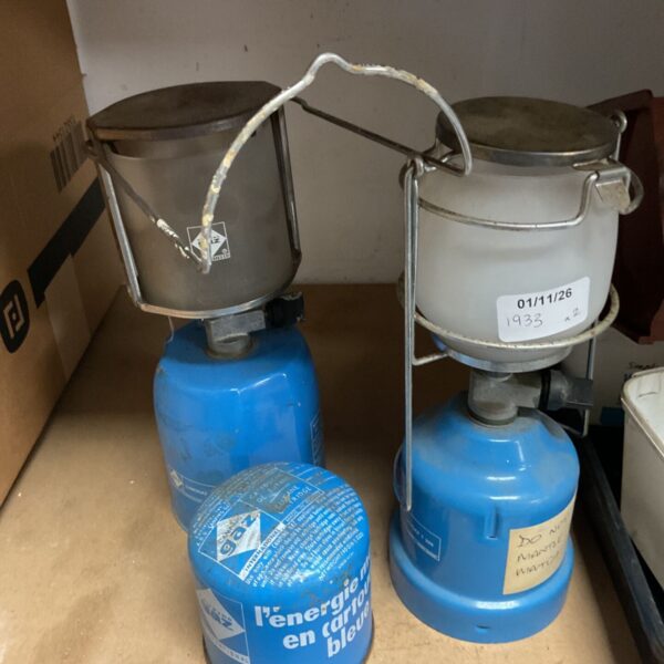 Two vintage Campingaz Lumogaz gas lanterns with blue gas cartridges and a spare cartridge